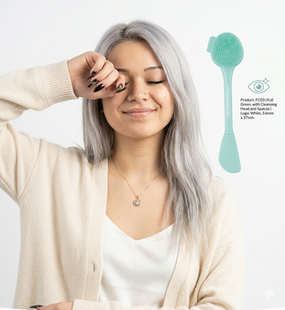Woman with gray hair holding a teal facial cleansing brush against a white background